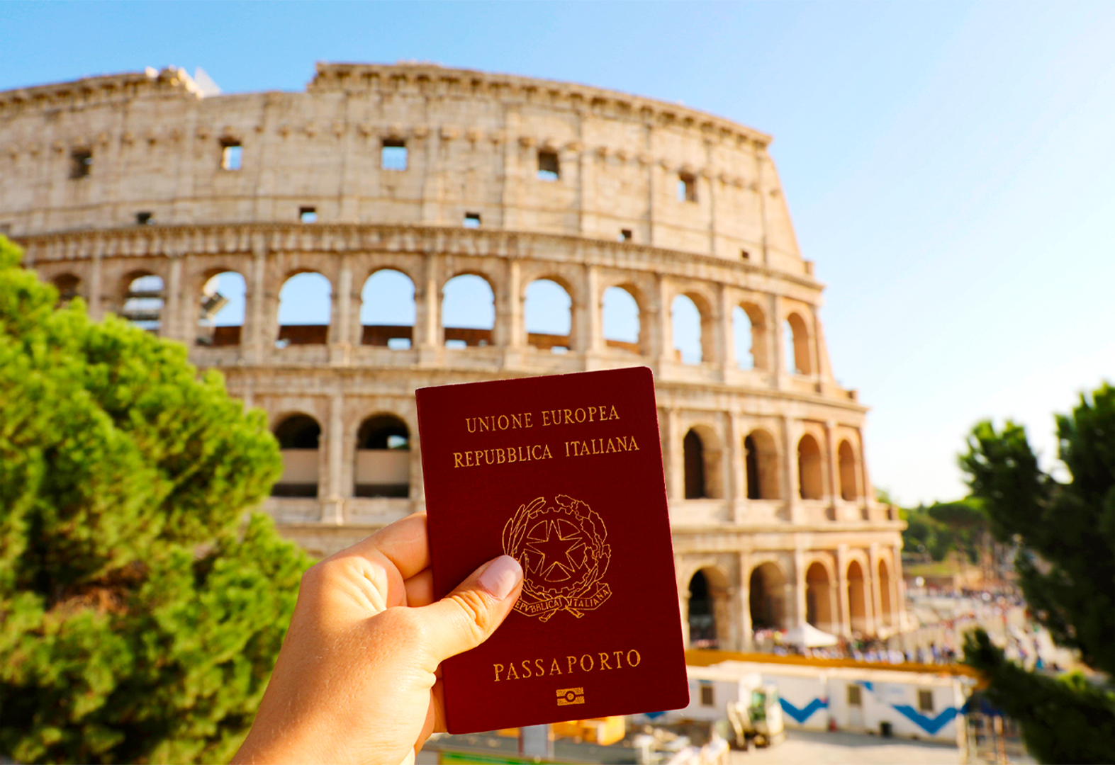 mão segurando o passaporte italiano em frente ao Coliseu, em Roma.